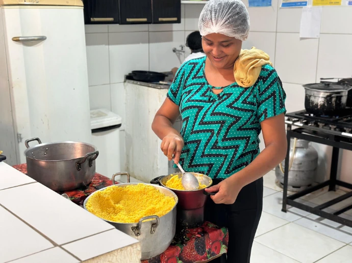 Mulher preparando alimentos em uma cozinha comunitária